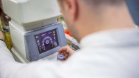 Optician adjusting autorefractor machine's settings.